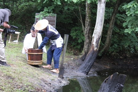 カグマですくい取り、桶に絞る。(昨年の黒川燃水祭の様子)